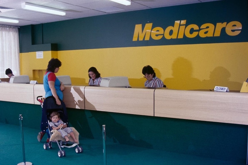 A photo of a woman and her child at a Medicare counter in the 1980s