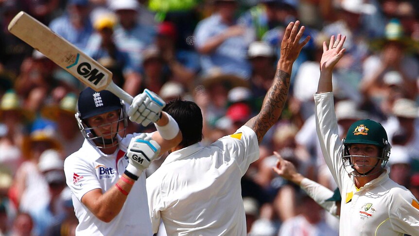 England's Joe Root (L) signals a DRS review as Australia celebrates his dismissal in Perth.
