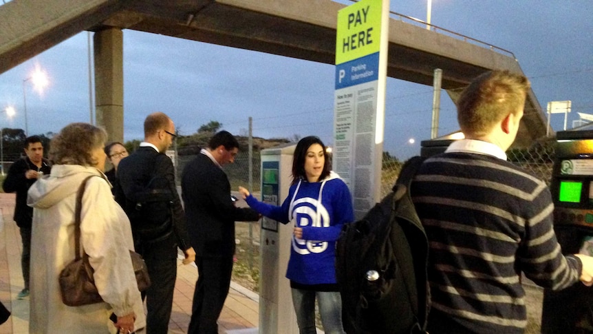 An assistant at Stirling train station explains to commuters in Perth how to pay on the first day of parking tickets