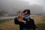 A security person moves journalists away from the Wuhan Institute of Virology