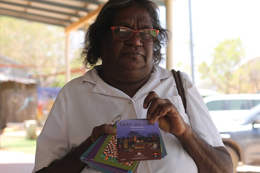 A woman holding up some cards with stories written on them