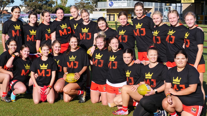 A group of women pose for a photo on a football ground