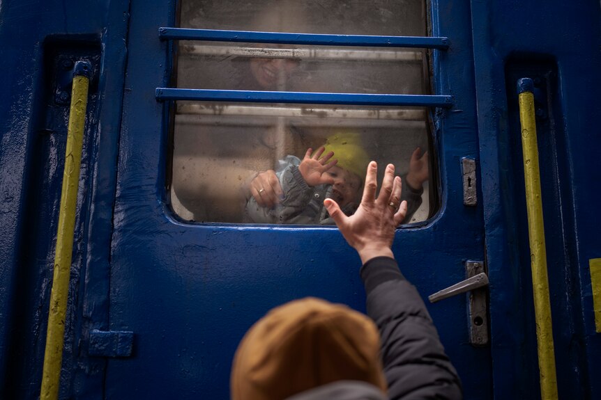 A man waves goodbye to his wife and child on a train