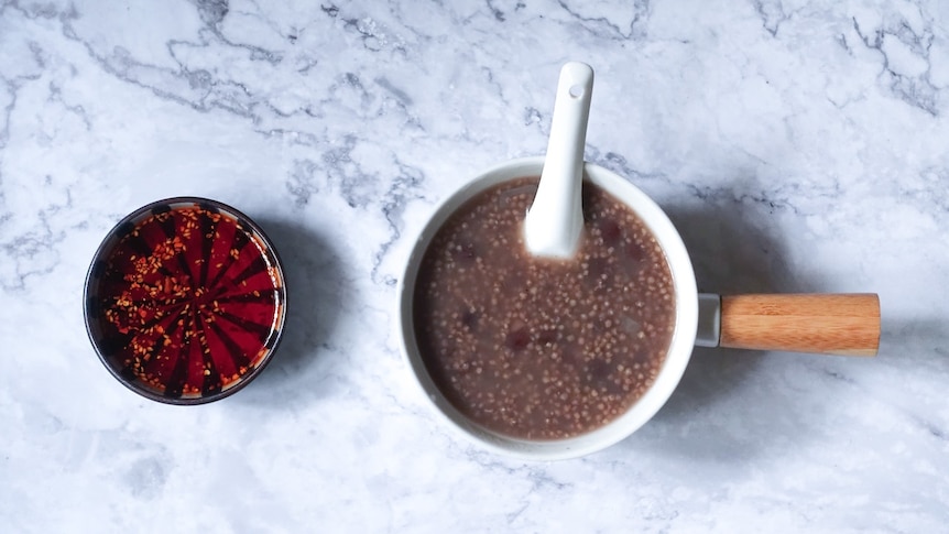 A flat lay shows one larger and smaller ceramic pots holding sauce over a white marble counter.