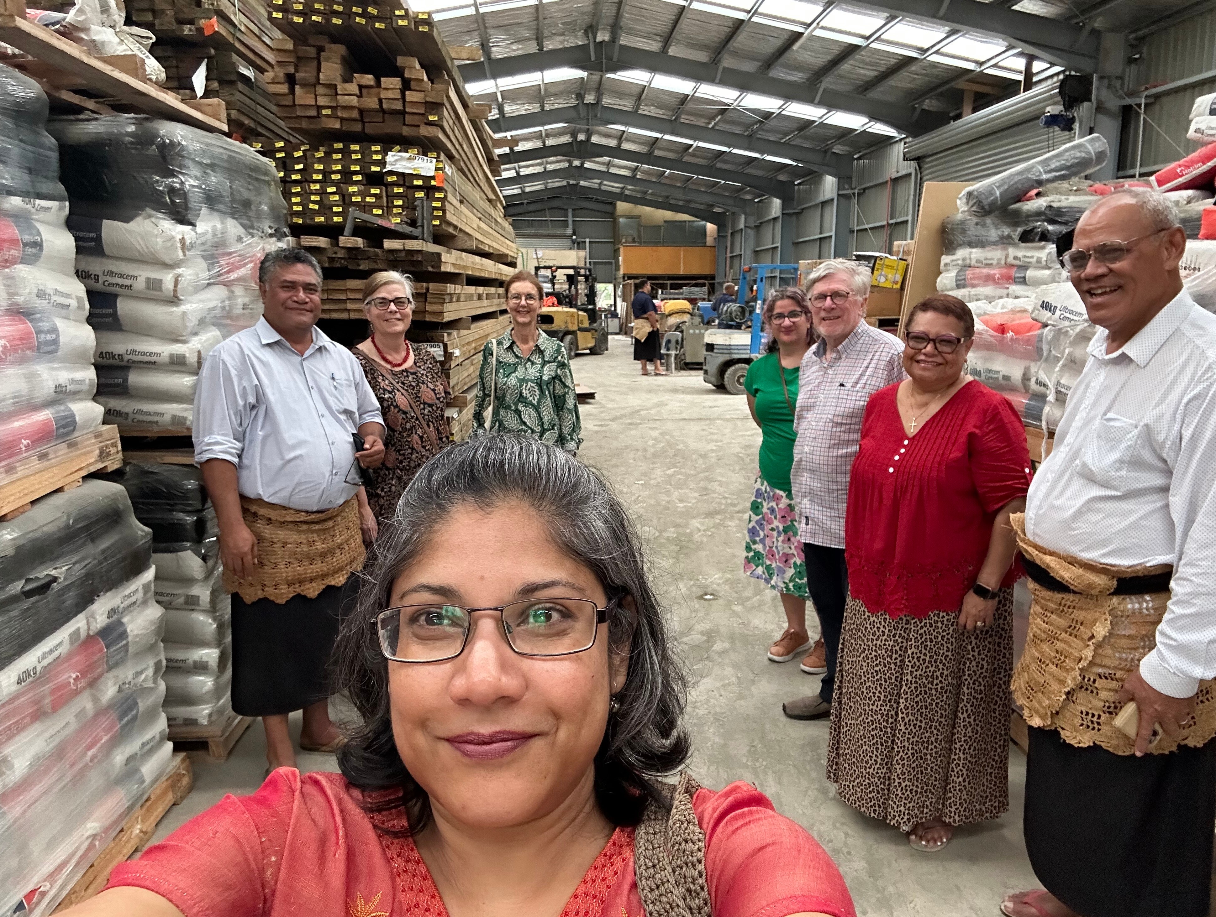 A photo of Dr Goringe inside a shed in Pacific with food donations, other members of the community standing behind her.