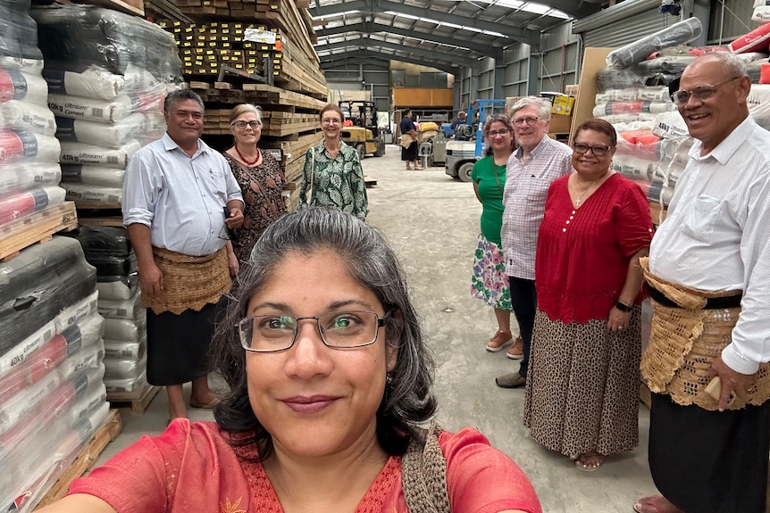 A photo of Dr Goringe inside a shed in Pacific with food donations, other members of the community standing behind her.