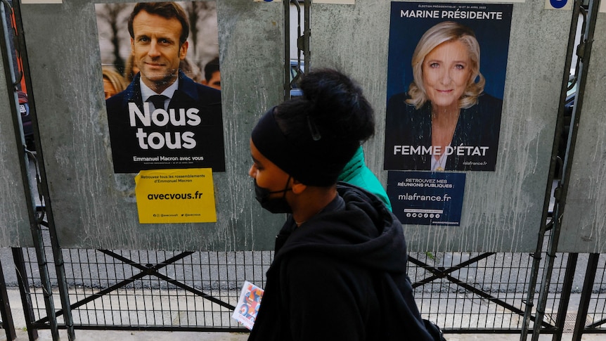 People walk past posters of Macron and Le Pen