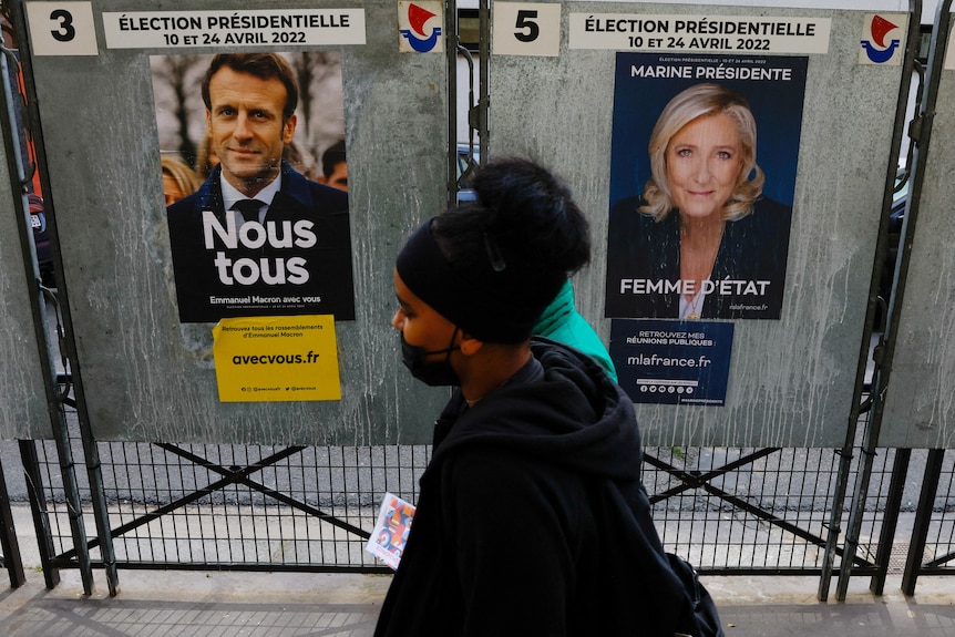 People walk past posters of Macron and Le Pen