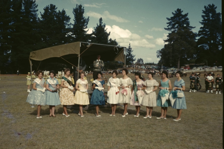 Historical photo from 1963 of a group of women lined up in a park all dressed nicely. 