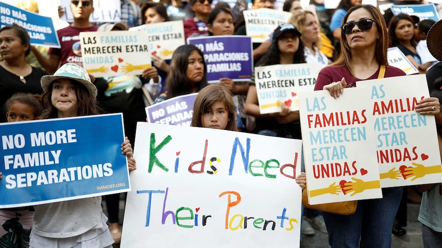 People hold signs stating 'kids need parents'.