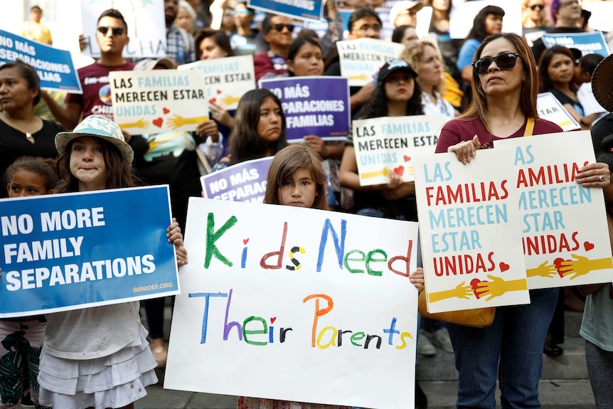 People hold signs stating 'kids need parents'.