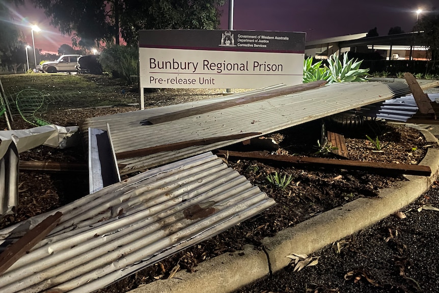 Twisted shets of corrugated iron in front of a Bunbury Regional Prison sign
