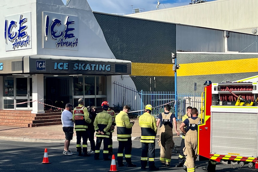 firefighters standing outside an Ice Arena building.