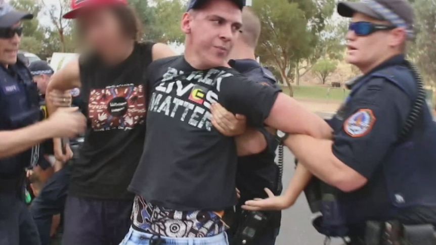 Dylvan Voller in handcuffs being arrested by police.