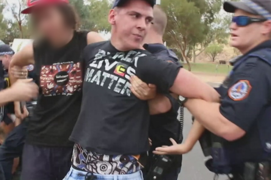 Dylvan Voller in handcuffs being arrested by police.