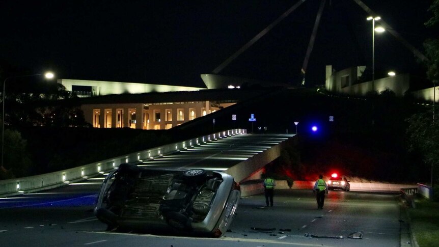 A car ron its side after rolling outside Parliament House.