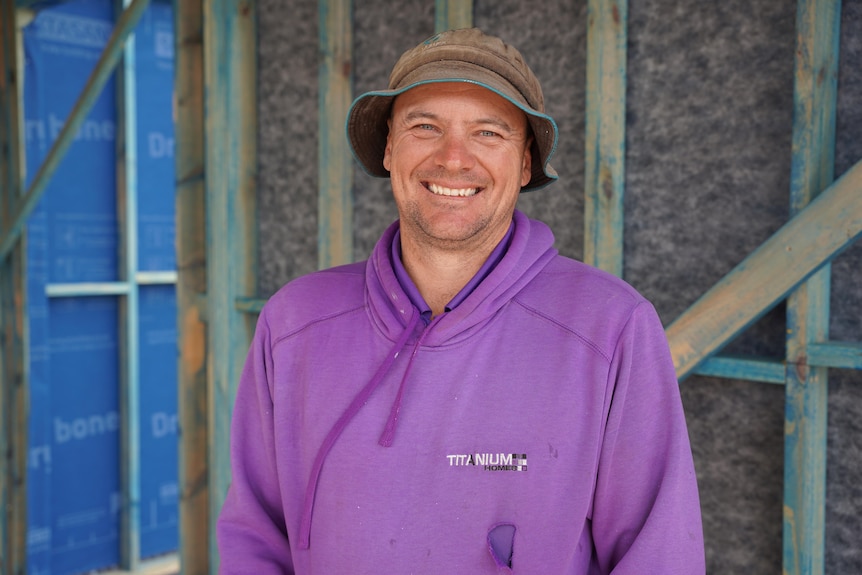 A man with a hat, dressed in a purple sweater