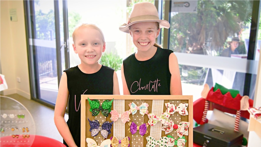 two young girls staning behind a display of christmas hair bows