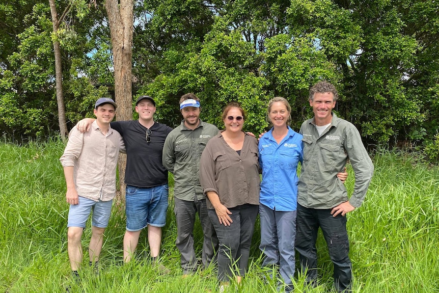 Several members from the wider team pose in grass at Belmonth Hill.