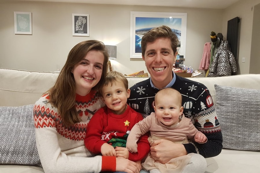 Family, parents with two young children, smile for a photograph. 