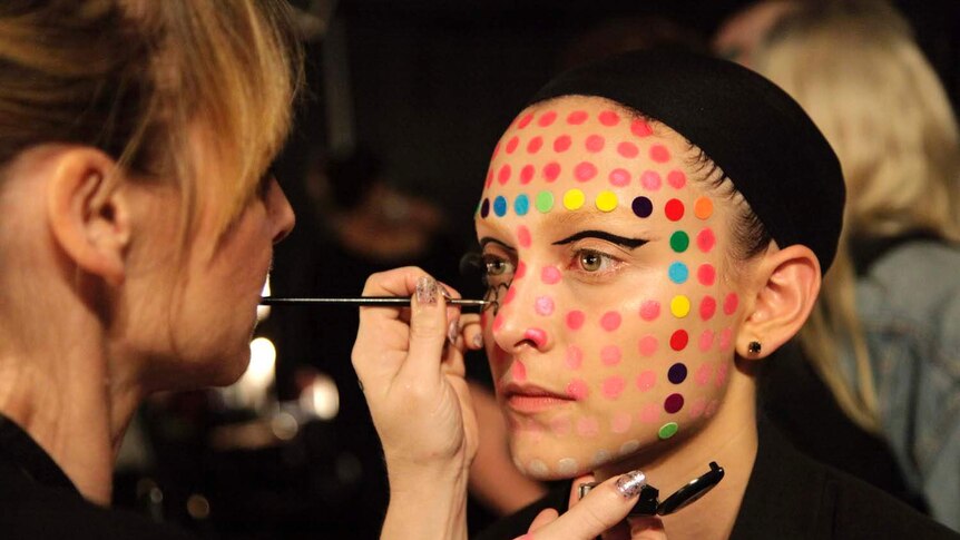 A model has makeup applied backstage
