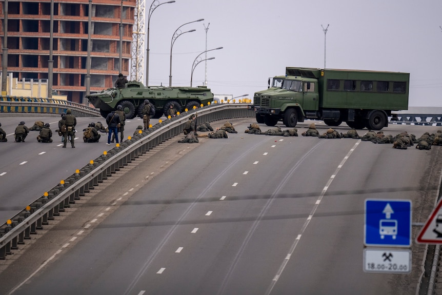 Two Ukrainian military vehicles and a line of troops taking position on a bridge in the capital, Kyiv.