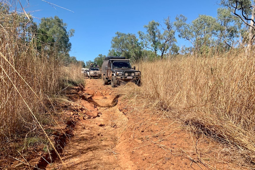 A four-wheel drive attempts to drive around a rutted track.