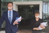 Darren Power and Lisa Bradley with tape over their mouths leaving Logan council chambers