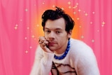 Harry Styles wearing a jumper and rings, looking at the camera.