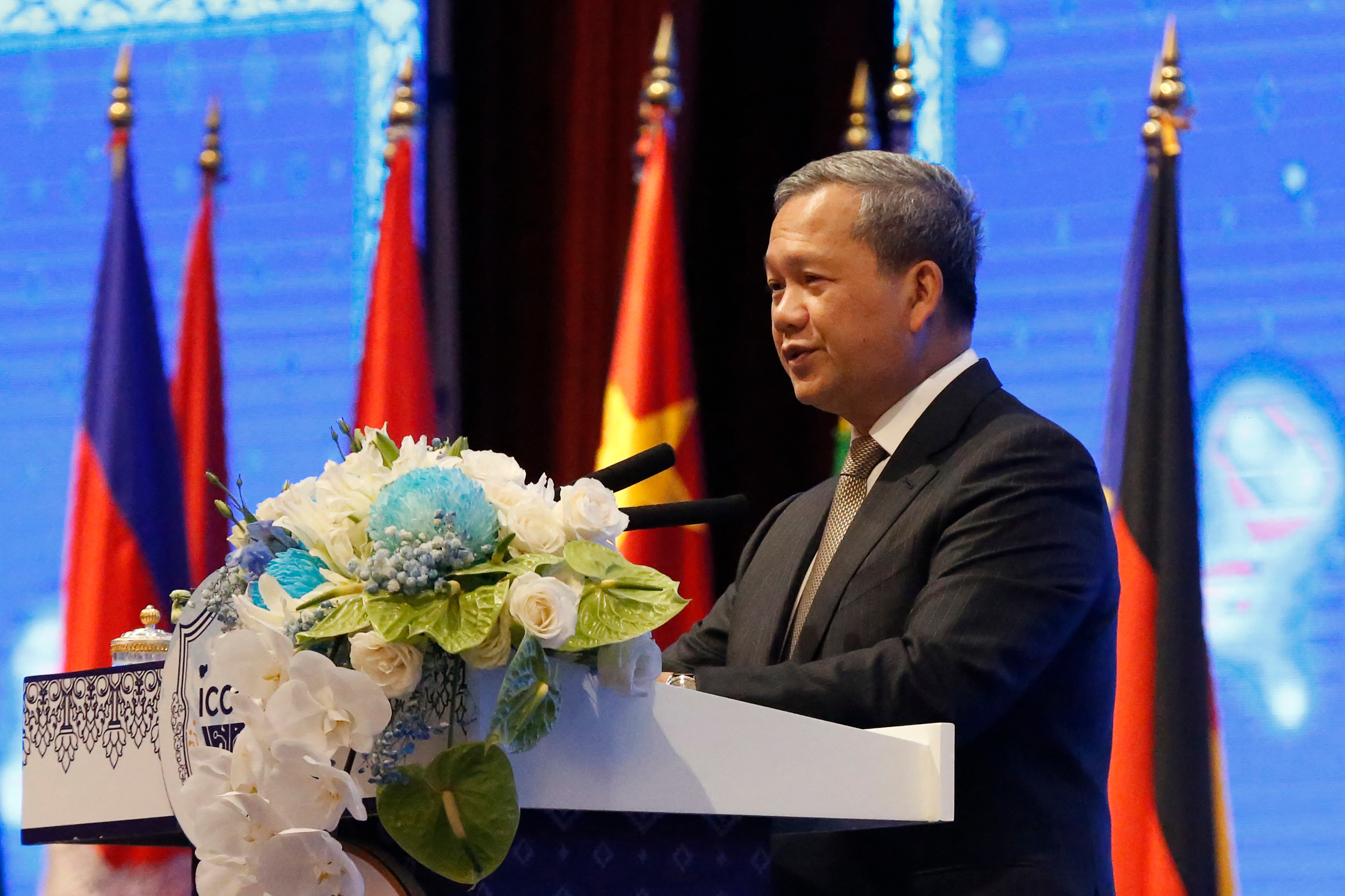 Hun Manet speaks behind a lectern in front of a series of flags.