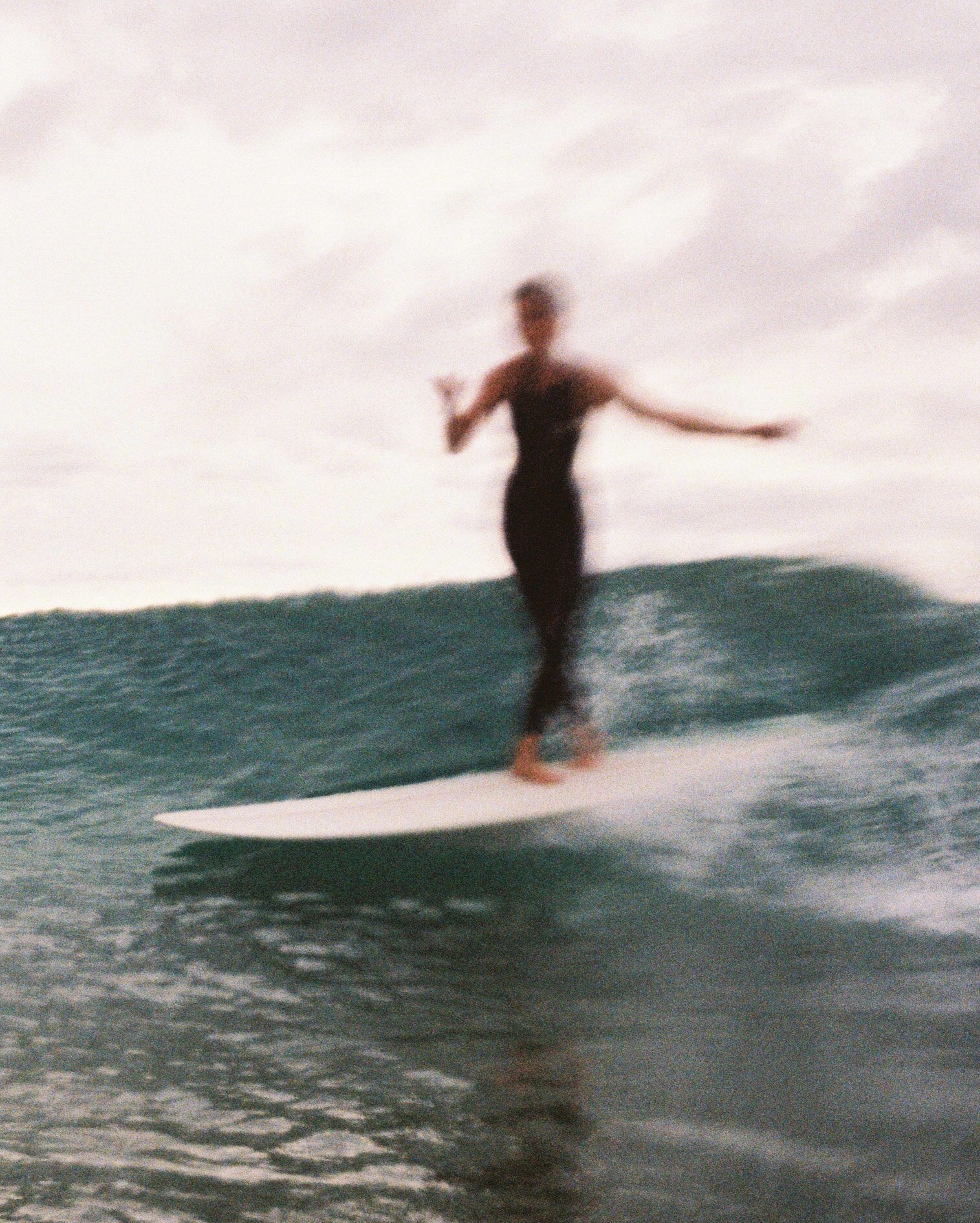 A blurred image of a female surfer on a wave