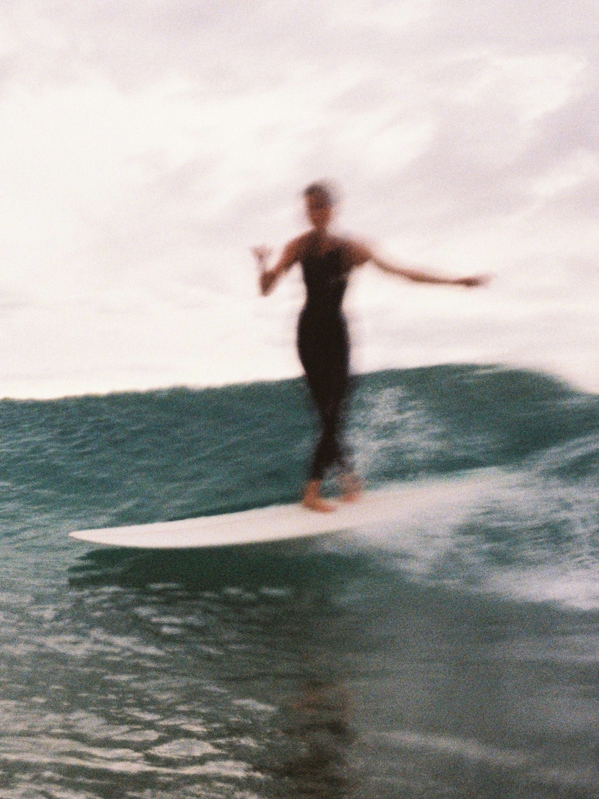 En suddig bild av en kvinnlig surfare på en våg