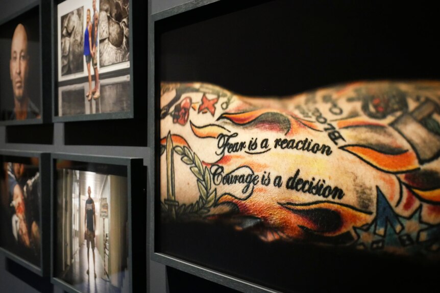 A framed photograph of a tattoo that reads "fear is a reaction, courage is a decision".