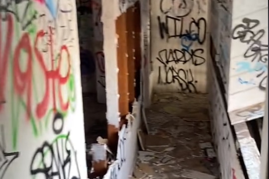 A hallway with multi-coloured graffiti on the walls and rubble on the floor