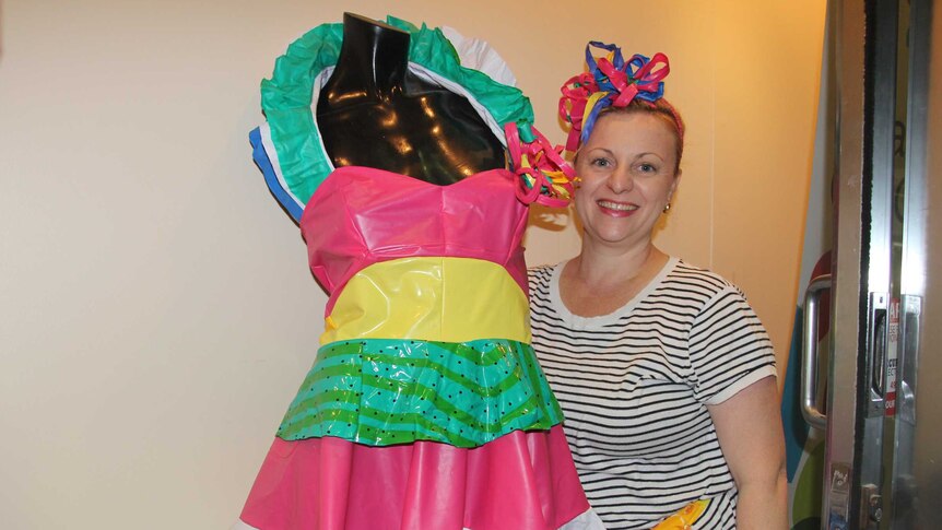 A woman stands in front of a mannequin in a colourful dress