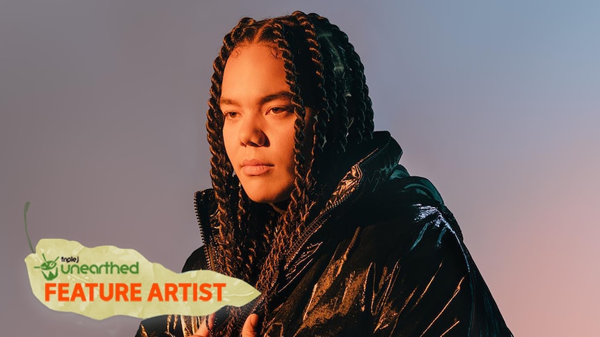 Jesswar, with long dark braids and a black jacket, stands in front of a purple gradient background looking past camera.