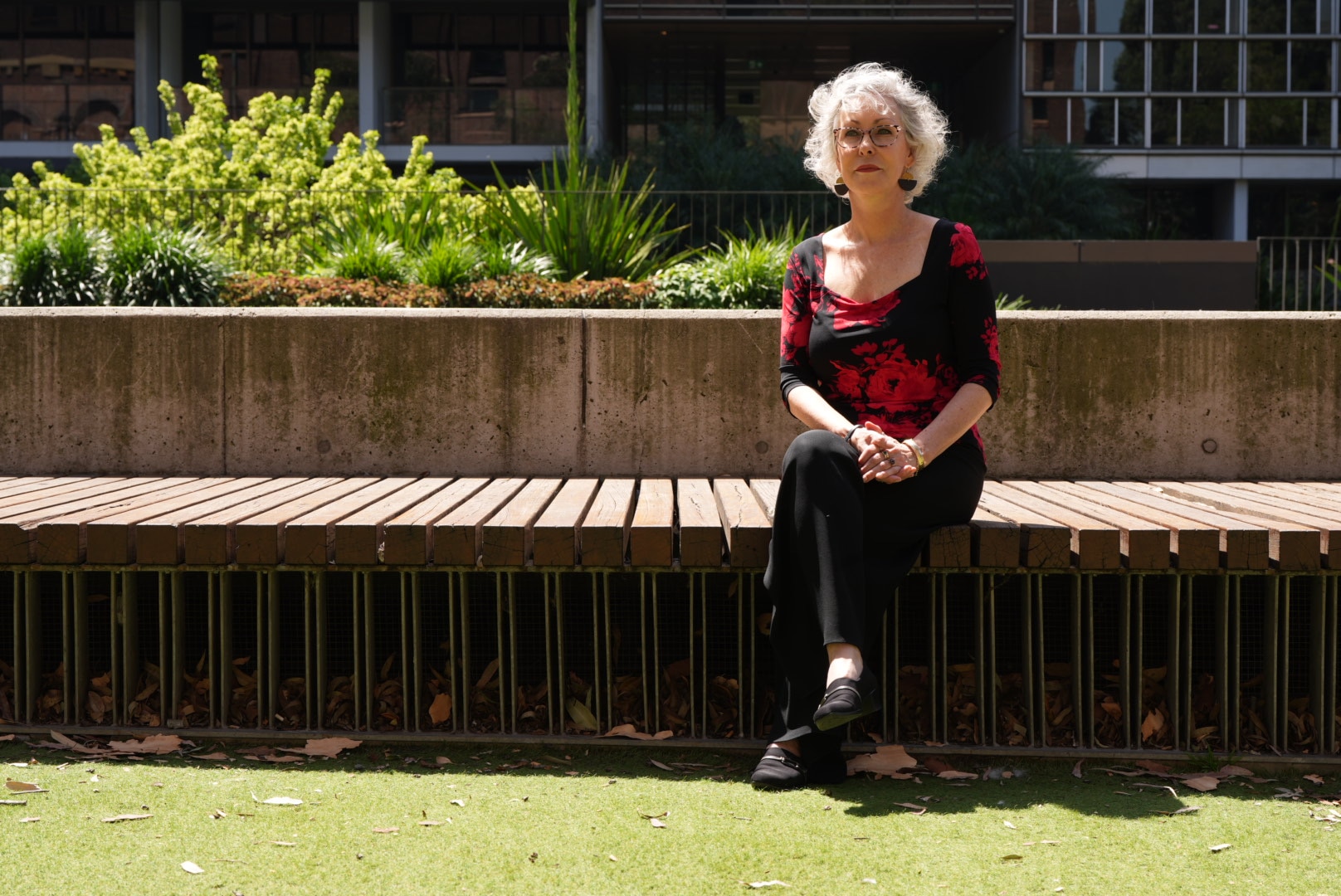 a woman with grey curly hair sits on a bench