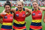Five Crows players stand arm in arm, smiling and celebrating their win.
