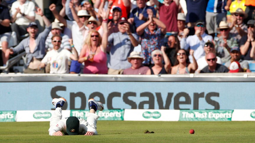 Australia' Marcus Harris puts his face in the grass after dropping a catch in the third Ashes Test at Headingley. Fans cheer.