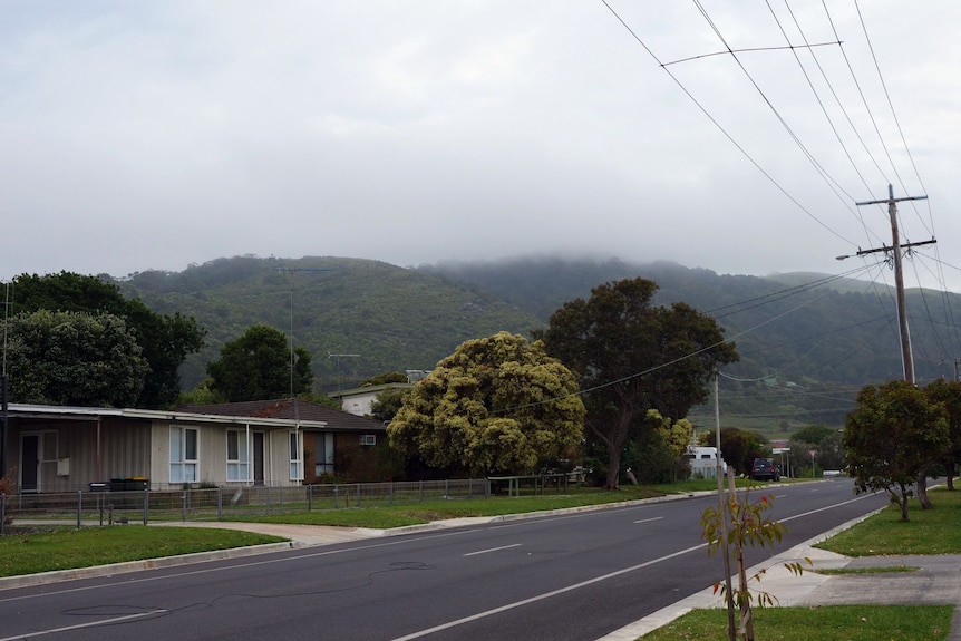 A streetscape with mountains shrouded in fog in the background.