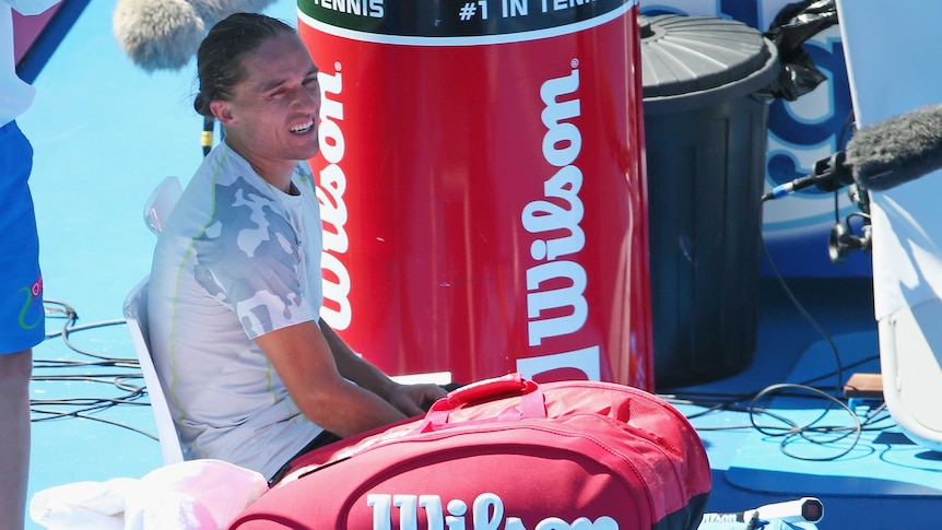 Alexandr Dolgopolov of Ukraine holds his injured leg after retiring injured during the Championship Match against Fernando Verdasco of Spain