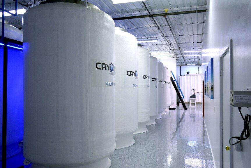 A row of large white tanks that each read "Cryonics Institute" in a line