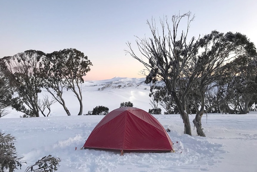 A red tent pitched in the snow.