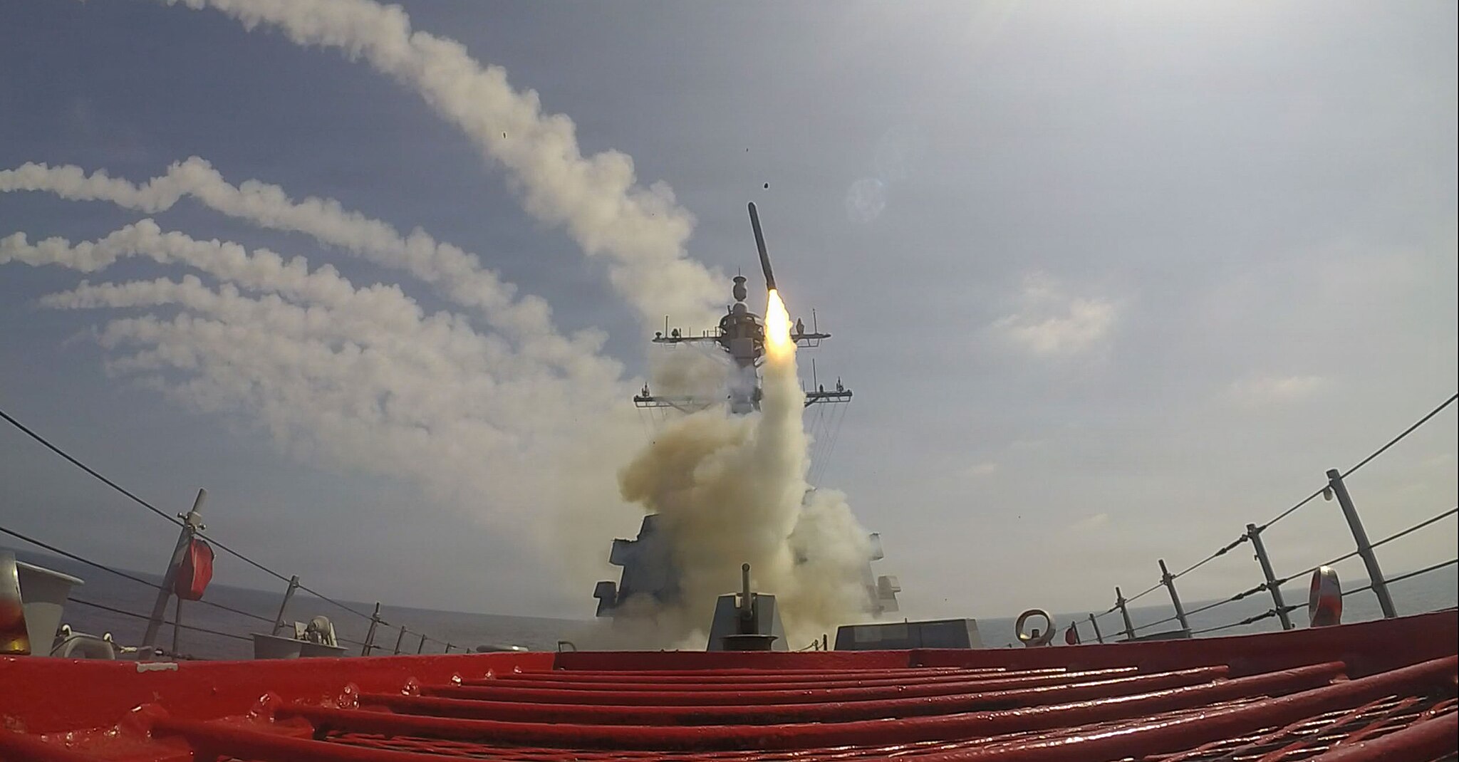 A missile is launched from a warship beneath a hazy sky.
