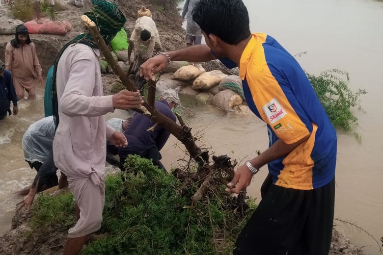 picture of flood affected men trying to move out of water