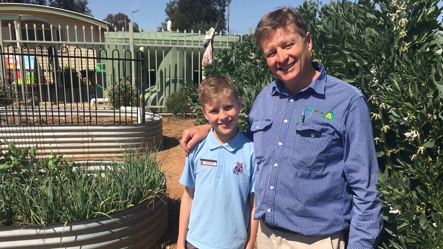 Angus and father Guy Webb stand together in a garden at Forbes North Public School.
