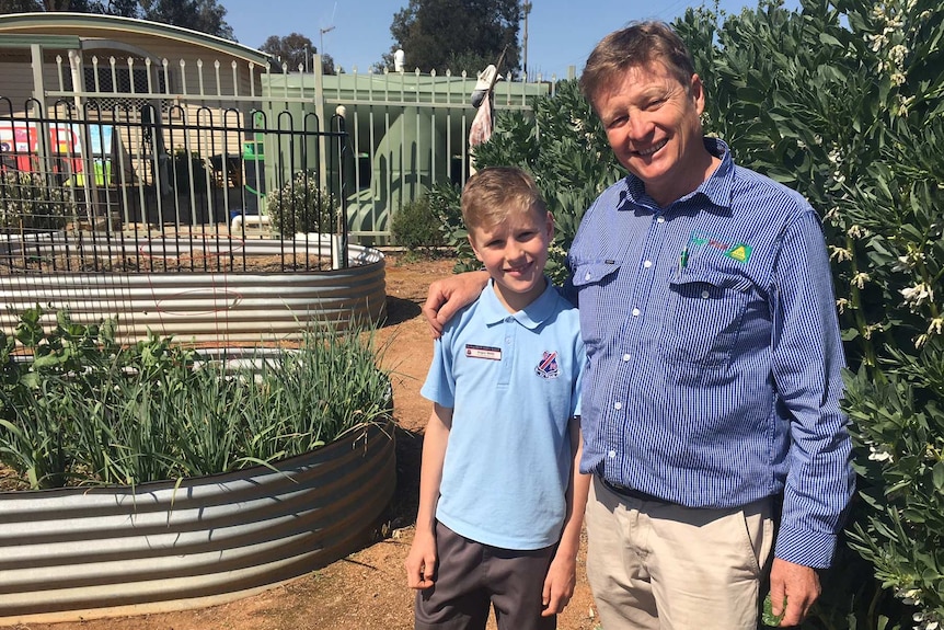Angus and father Guy Webb stand together in a garden at Forbes North Public School.