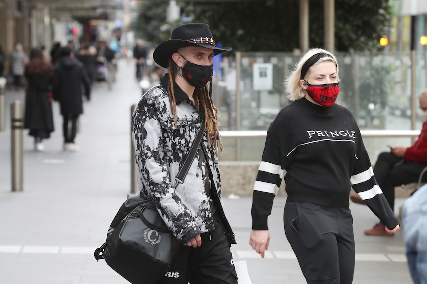 Two people walk through a mall wearing reusable masks.