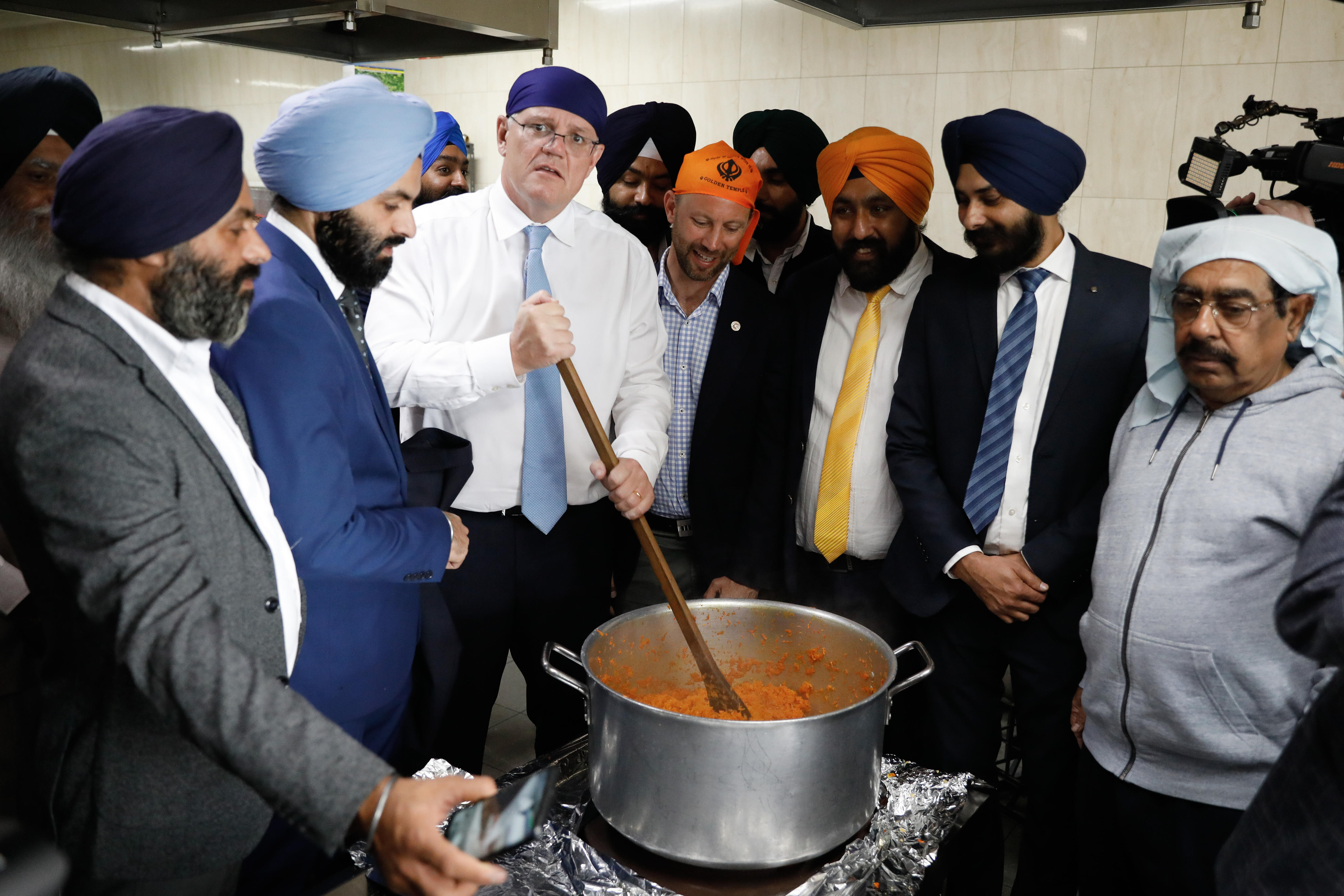 A man cooking rice surrounded by Sikh men