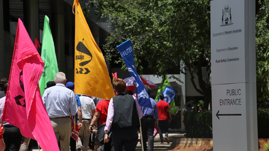 A view of marching protestors carrying flags from behind
